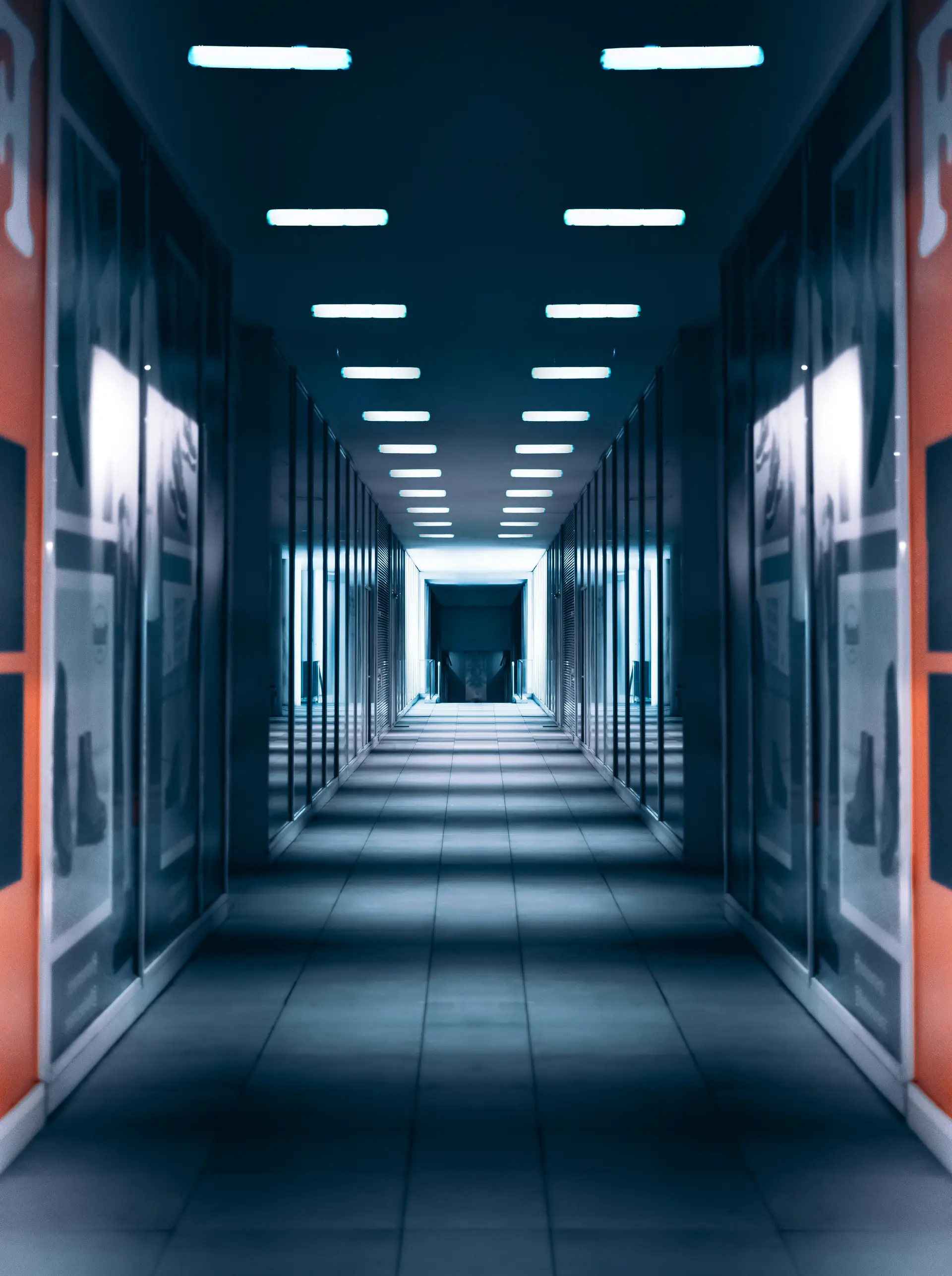 Cold aisle between two rows of racks in a data hall, lit from the ceiling along its full length.